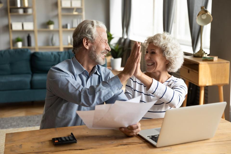 Two people gossip in front of a laptop.