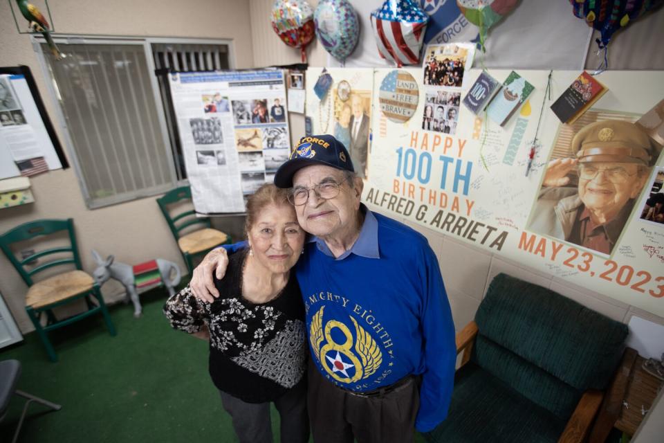 A man and woman stand with each other near posters with photos of the man.