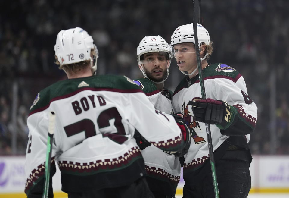 Arizona Coyotes' Jakob Chychrun (6), Shayne Gostisbehere (14) and Travis Boyd (72) celebrate Chychrun's goal against the Vancouver Canucks during the second period of an NHL hockey game Saturday, Dec. 3, 2022, in Vancouver, British Columbia. (Darryl Dyck/The Canadian Press via AP)