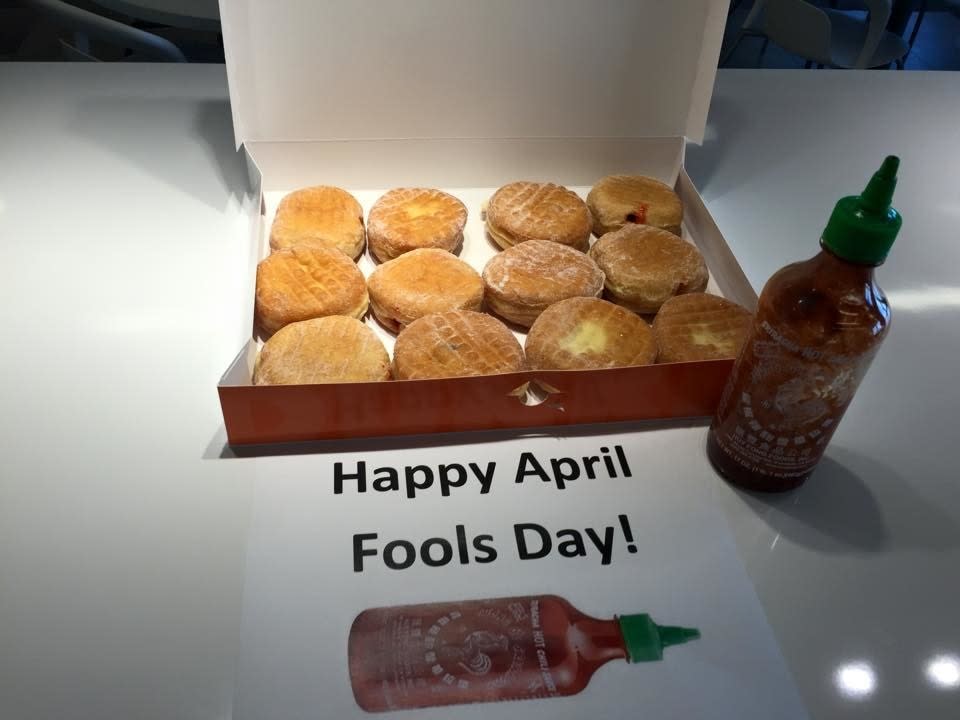 Box of round pastries next to a hot sauce bottle with a label "Happy April Fools Day"