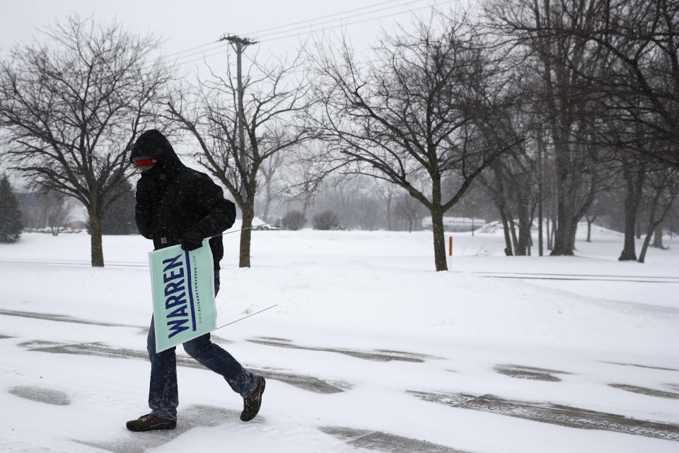 Volunteer Erick Zehr carries campaign signs outside a venue as snow falls before an event with Democratic presidential candidate Sen. Elizabeth Warren, D-Mass., Friday, Jan. 17, 2020, in Newton, Iowa. (AP Photo/Patrick Semansky)