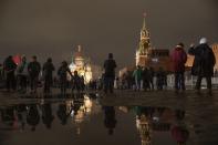 People walk in the Red Square prior to its closure for celebrations on the New Year's Eve, with the St. Basil's Cathedral, left, and the Spasskaya Tower, right, in Moscow, Russia, Saturday, Dec. 31, 2022. (AP Photo/Alexander Zemlianichenko)