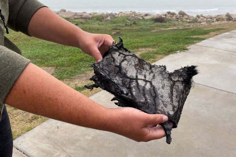 A spectator holds a piece of debris which was blown 5 miles from the site where SpaceX test rocket SN11 exploded upon landing, in Boca Chica