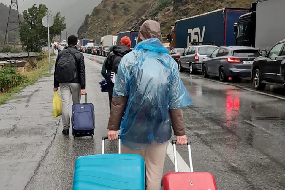 <div class="inline-image__caption"><p>People carrying luggage walk past vehicles with Russian license plates on the Russian side of the border towards the Nizhniy Lars customs checkpoint between Georgia and Russia some 25 km outside the town of Vladikavkaz, on September 25, 2022.</p></div> <div class="inline-image__credit">AFP/Getty</div>