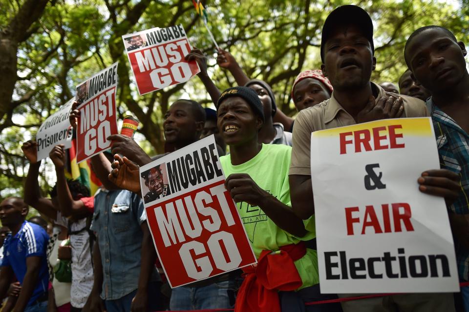 Protesters hold signs during a gathering in Zimbabwe's capital of Harare on Nov. 21, 2017, calling for Mugabe to step down. (Photo: TONY KARUMBA via Getty Images)