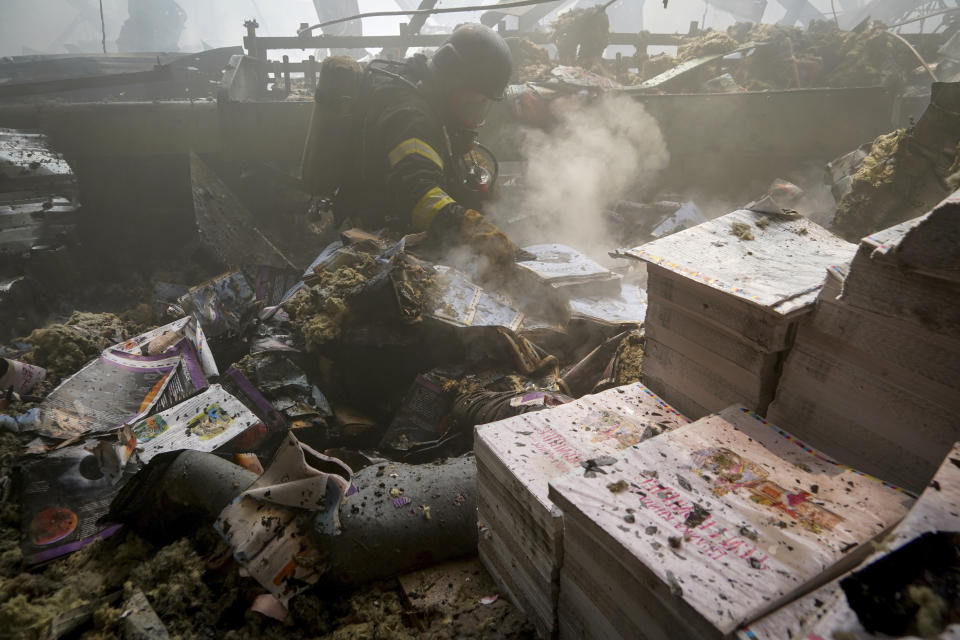 Firefighters work to extinguish a fire as a lifeless body lies under the rubble after a Russian missile hit a large printing house in Kharkiv, Ukraine, Thursday, May 23, 2024. Russian missiles slammed into Ukraine’s second-largest city in the northeast of the country and killed at least seven civilians early Thursday, officials said, as Kyiv’s army labored to hold off an intense cross-border offensive by the Kremlin’s larger and better-equipped forces. (AP Photo/Andrii Marienko)