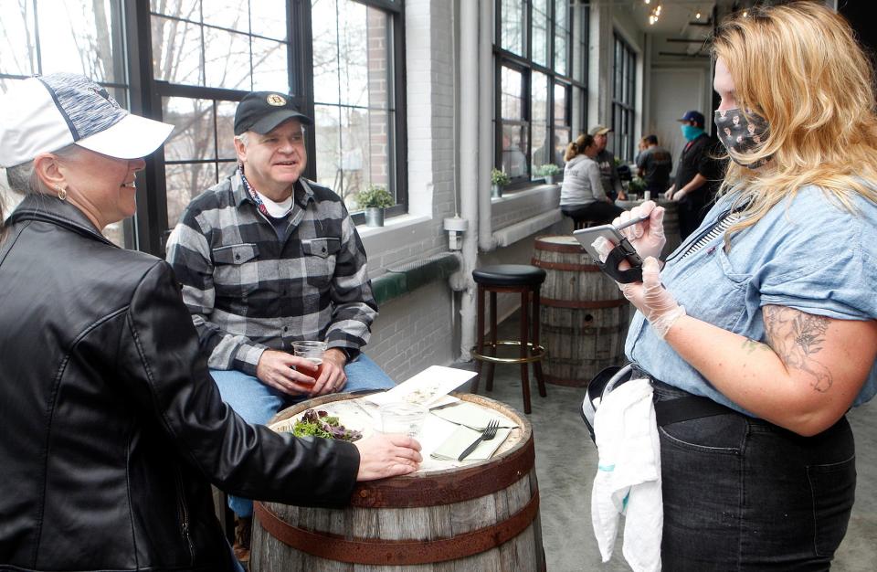 Waitress Kim Boya (right) waits on Carla and Brian Gilmartin of Auburn during the grand opening of the Medusa Brewing Company at the Landing at Hudson Mills, Nov. 14, 2020. 