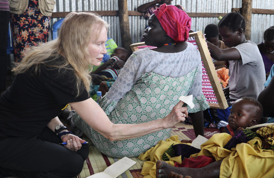 In this photo taken Tuesday, April 2, 2019, human rights activist Mia Farrow plays with a baby lying on his mother's lap while speaking to a group of women during a visit to an internally displaced person's camp in the capital Juba, South Sudan. Human rights activist Mia Farrow spoke to The Associated Press as she visited South Sudan again in her new role as envoy for the International Rescue Committee, helping the aid group to promote a global initiative to change the way humanitarian organizations approach malnutrition. (AP Photo/Sam Mednick)