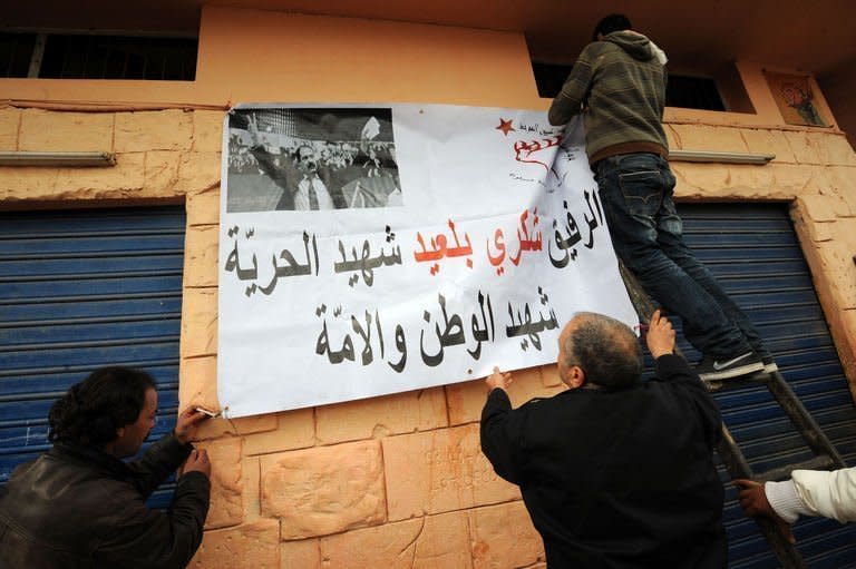 Tunisians fix a poster featuring late opposition leader Chokri Belaid during his funeral procession Djebel Jelloud district of Tunis, on February 8, 2013. Tunisian police have fired tear gas and clashed with protesters as tens of thousands joined the funeral of Belaid whose murder plunged the country into new post-revolt turmoil