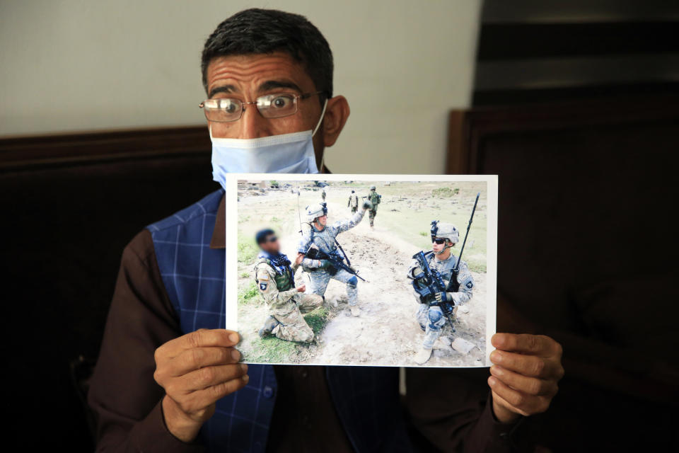 In this Friday, April 30, 2021, photo Ayazudin Hilal, 40, a former Afghan interpreter for the U.S. show his picture with the US Army soldiers during an interview to The Associated Press after a protest against the U.S. government and NATO in Kabul, Afghanistan. (AP Photo/Mariam Zuhaib)