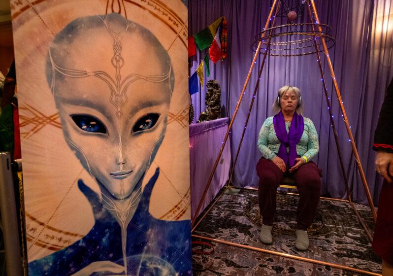 LOS ANGELES, CA-February 9, 2024: Carol Chappell, from Sedona, Arizona, sits inside a pyramid known as a multi dimensional healing chamber enhanced by tensor rings on display at the Conscious Life Expo at the LAX Hilton Hotel in Los Angeles. (Mel Melcon / Los Angeles Times)