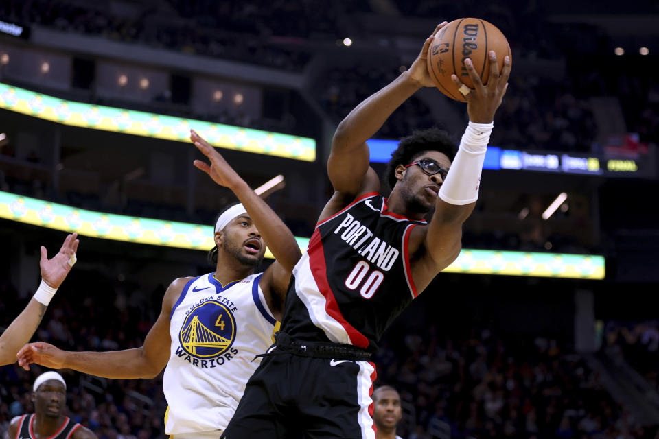 Portland Trail Blazers guard Scoot Henderson (00) rebounds the ball next to Golden State Warriors guard Moses Moody (4) during the first half of an NBA basketball game in San Francisco, Wednesday, Dec. 6, 2023. (AP Photo/Jed Jacobsohn)