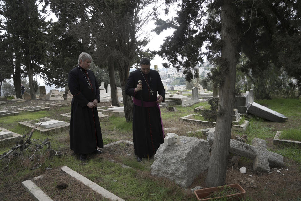 Hosam Naoum, a Palestinian Anglican bishop, right, stands with a colleague where vandals desecrated more than 30 graves at a historic Protestant Cemetery on Jerusalem's Mount Zion in Jerusalem, Wednesday, Jan. 4, 2023. Israel's foreign ministry called the attack an "immoral act" and "an affront to religion." Police officers were sent to investigate the profanation. (AP Photo/ Mahmoud Illean)