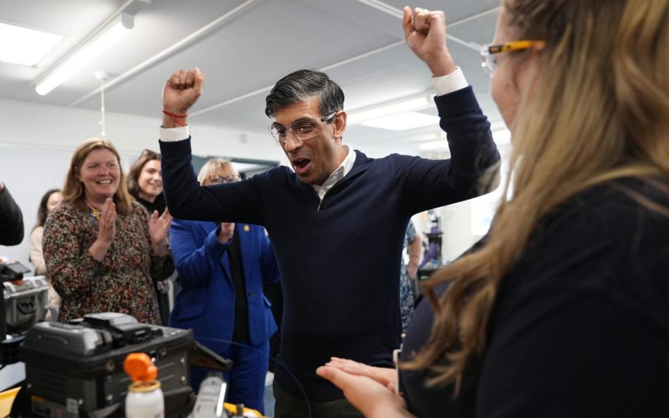 Rishi Sunak celebrates after being shown how to splice a wire by field service engineer apprentice in Liskeard, Cornwall