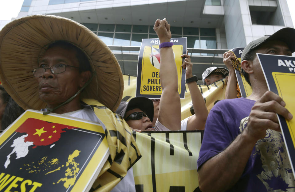 Protesters shout slogans during a rally outside the Chinese consulate at the financial district of Makati city east of Manila, Philippines Wednesday, April 2, 2014. Dozens of Filipino left-wing activists protested at China's consulate to protest the blocking by Chinese coast guard ships of a Philippine supply boat near a disputed shoal in the South China Sea. (AP Photo/Bullit Marquez)