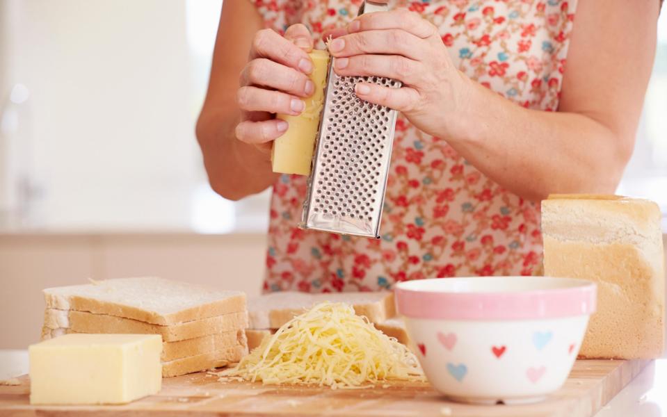 Person grating cheese in the kitchen - Credit: Alamy