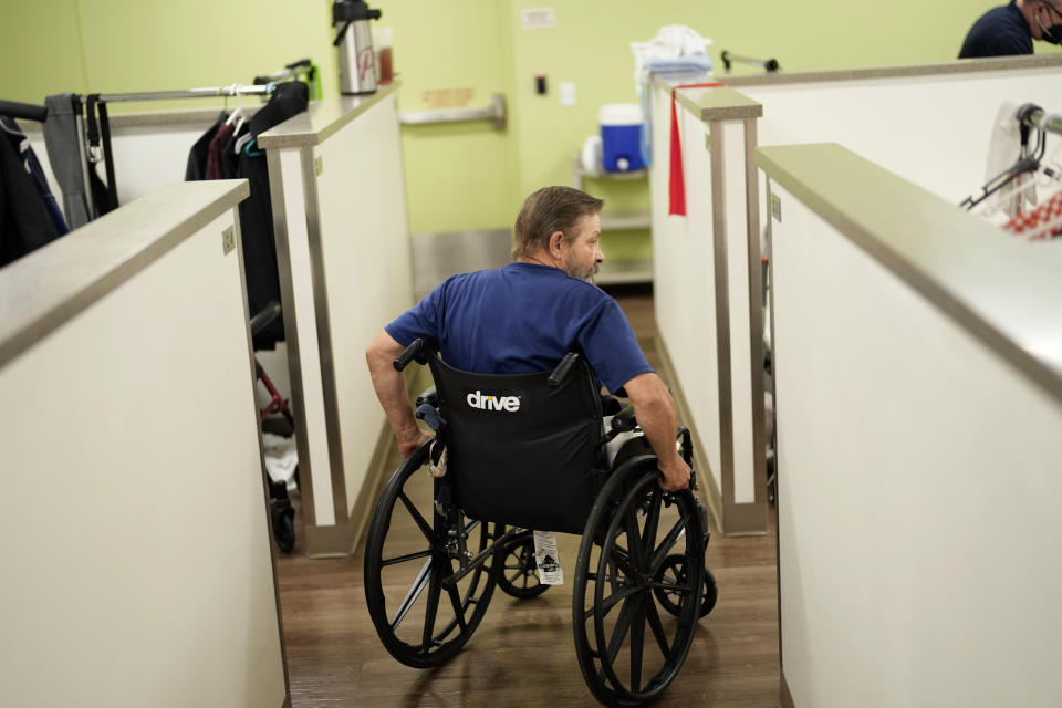 Ron Falk, 62, uses his wheelchair to navigate the corridors of his temporary lodging, Tuesday, June 25, 2024 in Phoenix. Falk lost his right leg, had extensive skin grafting on the left one and is still recovering a year after collapsing on the searing asphalt outside a convenience store where he stopped for a cold soda during a blistering heat wave. (AP Photo/Matt York)