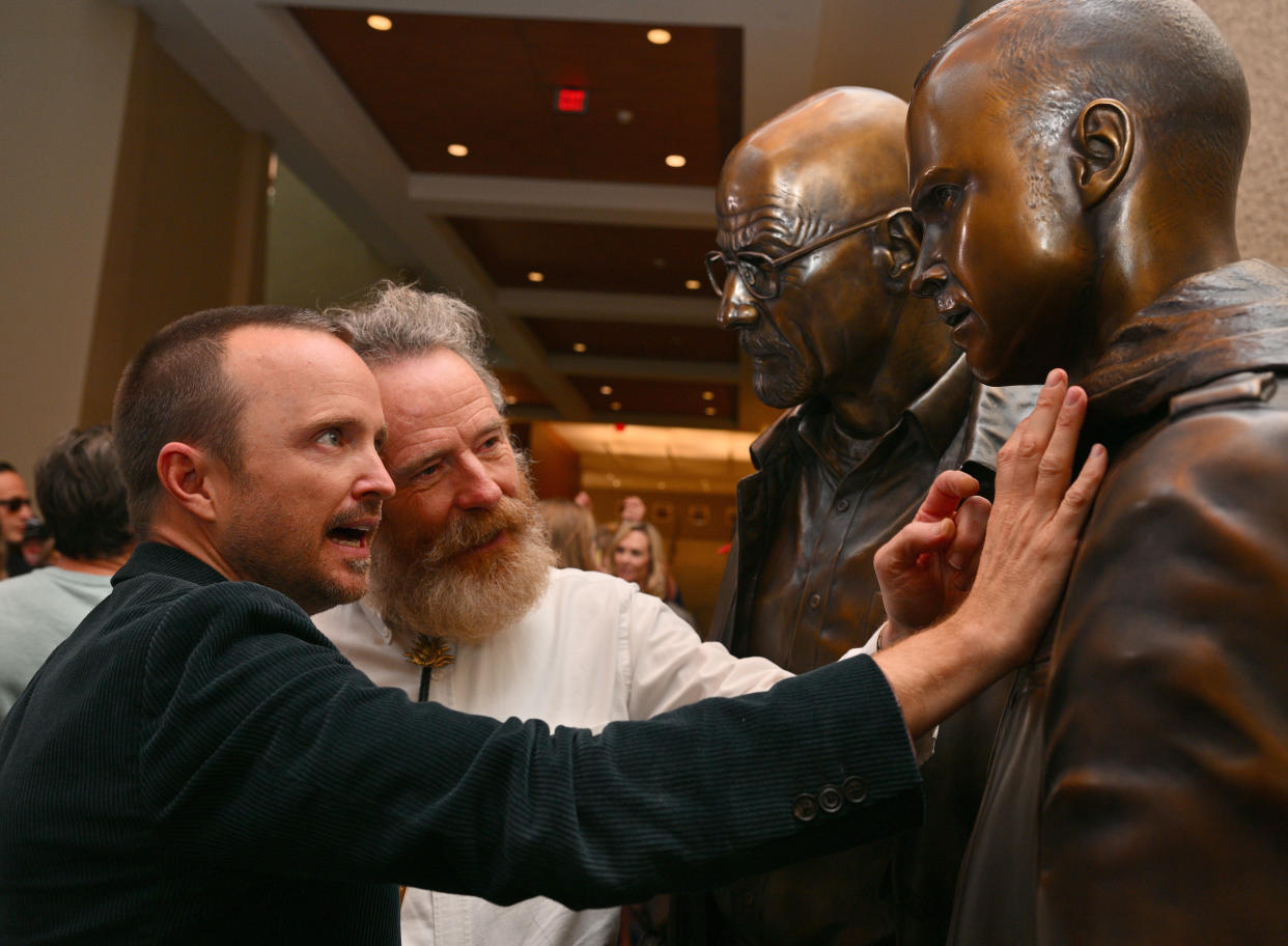 ALBUQUERQUE, NEW MEXICO - JULY 29:  Actor Aaron Paul (L) and actor Bryan Cranston examine bronze statues depicting television characters Walter White, played by Cranston, and Jesse Pinkman, played by Paul, from the series 