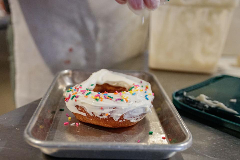 Crystal Leduc, the new co-owner of SōDOUGH Baking Co., puts sprinkles on top of a frosted donut Thursday, Feb. 3, 2022.