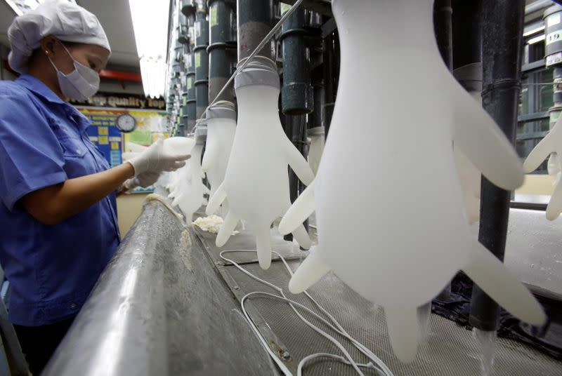 FILE PHOTO: A worker inspects gloves at a Top Glove factory outside Kuala Lumpur