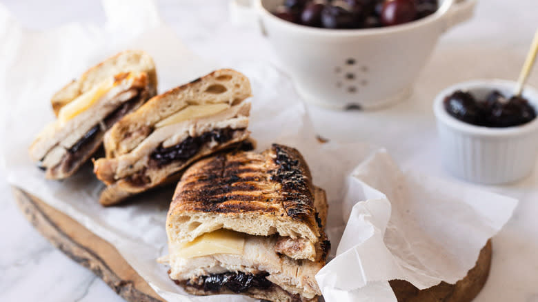 Three slices of panini on parchment paper with cherry chutney and cherries