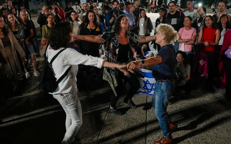 People react as they hear the news of the release of 13 Israeli hostages held by Hamas in the Gaza strip, in Tel Aviv, Israel, on Friday, Nov. 24, 2023. Friday marks the start of a four-day cease-fire in the Israel-Hamas war, during which the Gaza militants pledged to release 50 hostages in exchange for 150 Palestinians imprisoned by Israel. ()