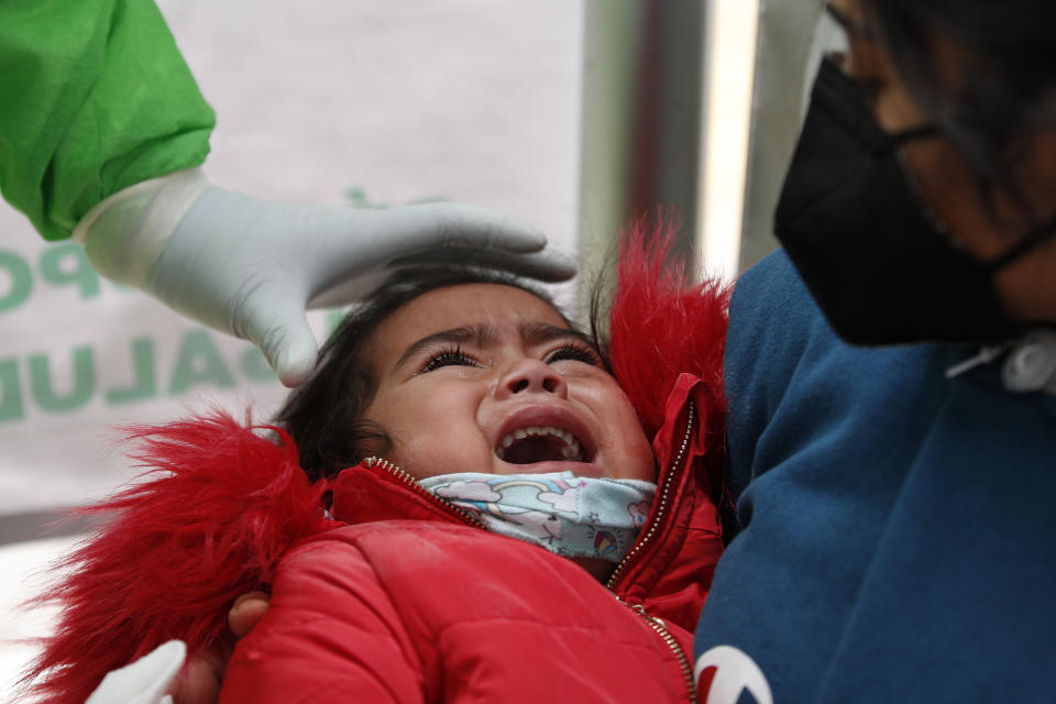 A girl cries after having a nasal swab collected for a rapid COVID-19 test, at a health post set up by the city's Ministry of Health at the TAPO bus station in the Venustiano Carranza borough of Mexico City, Friday, Nov. 20, 2020. Mexico passed the 100,000 mark in confirmed COVID-19 deaths on Thursday, becoming only the fourth country to do so. (AP Photo/Rebecca Blackwell)