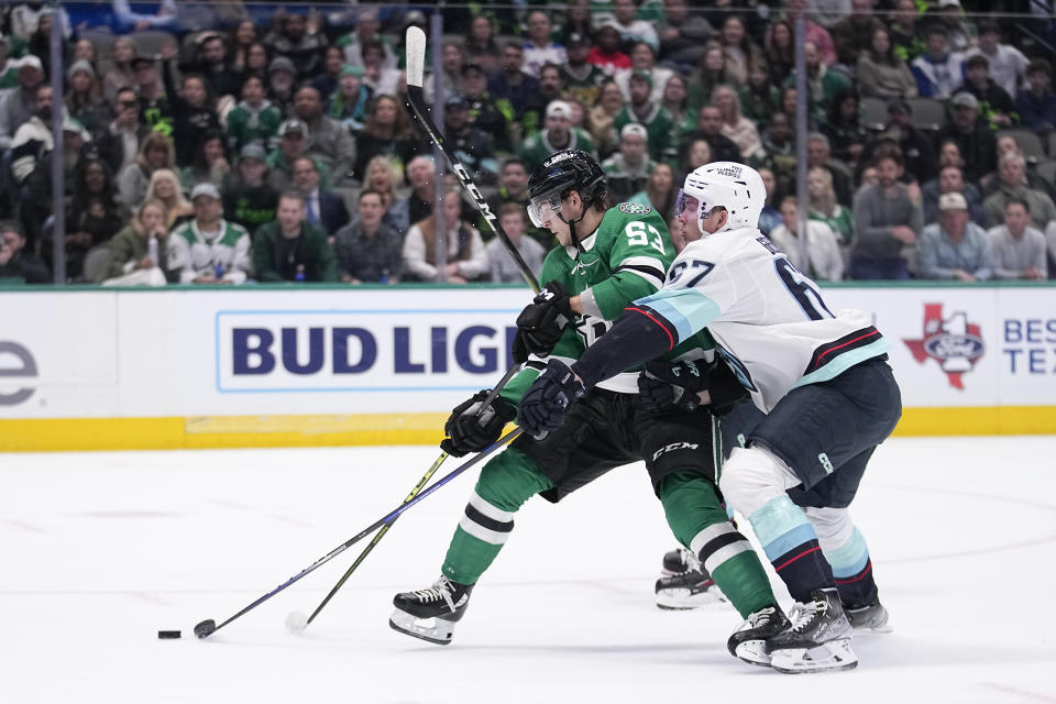 Dallas Stars center Wyatt Johnston (53) works agasinst Seattle Kraken center Morgan Geekie (67) to take a shot inthe first period of an NHL hockey game, Tuesday, March 21, 2023, in Dallas. (AP Photo/Tony Gutierrez)