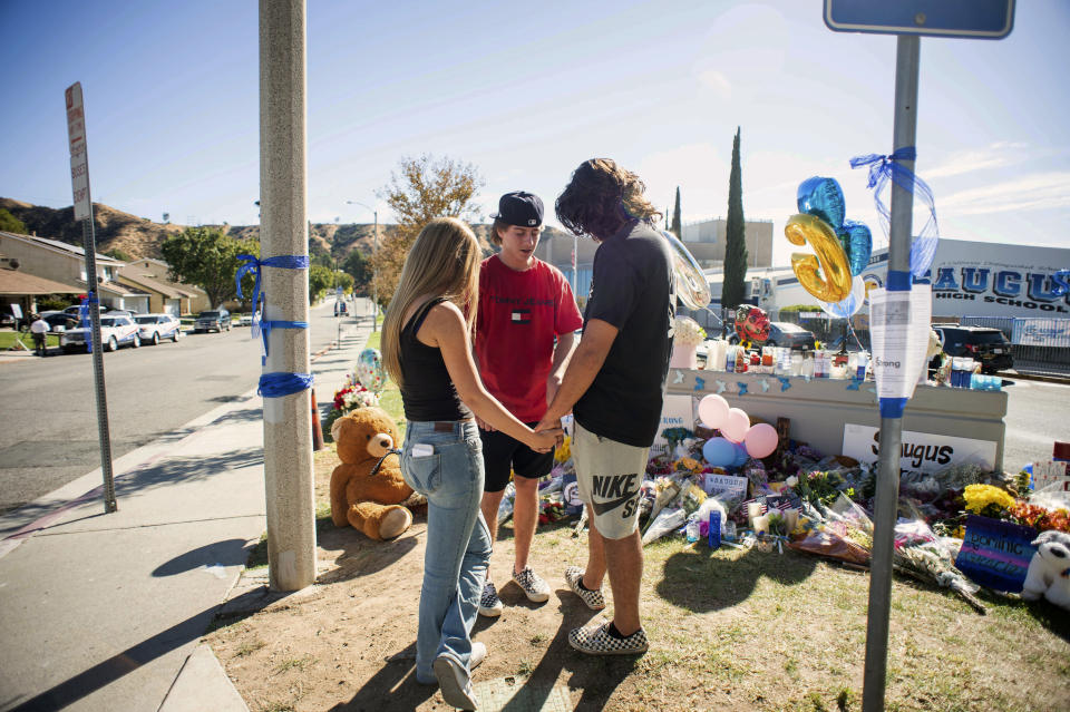 Students Britney Hopkins, Evan Jabbaz and Connor Nassry, all 16, pray at a memorial, Monday, Nov. 18, 2019, for two students killed during a shooting at Saugus High School in Santa Clarita, Calif., several days earlier. Students will return to school on Dec. 2. (Sarah Reingewirtz/The Orange County Register via AP)