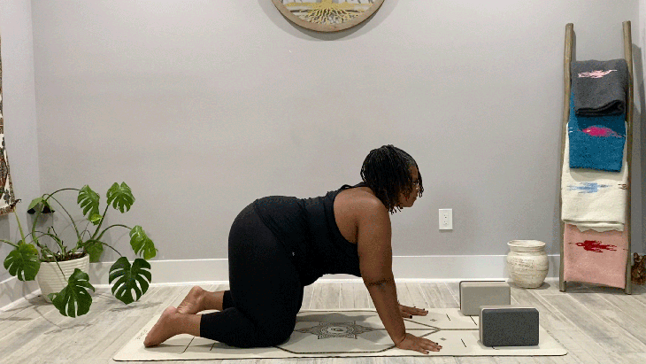 Woman on her hands and knees in Cow Pose with a slight backbend on her yoga mat