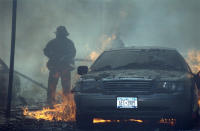 A fireman battles to put out the flames tearing through a nearby vehicle. (Caters)