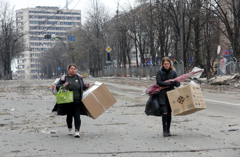 FILE PHOTO: Women carry belongings in a street in Mariupol