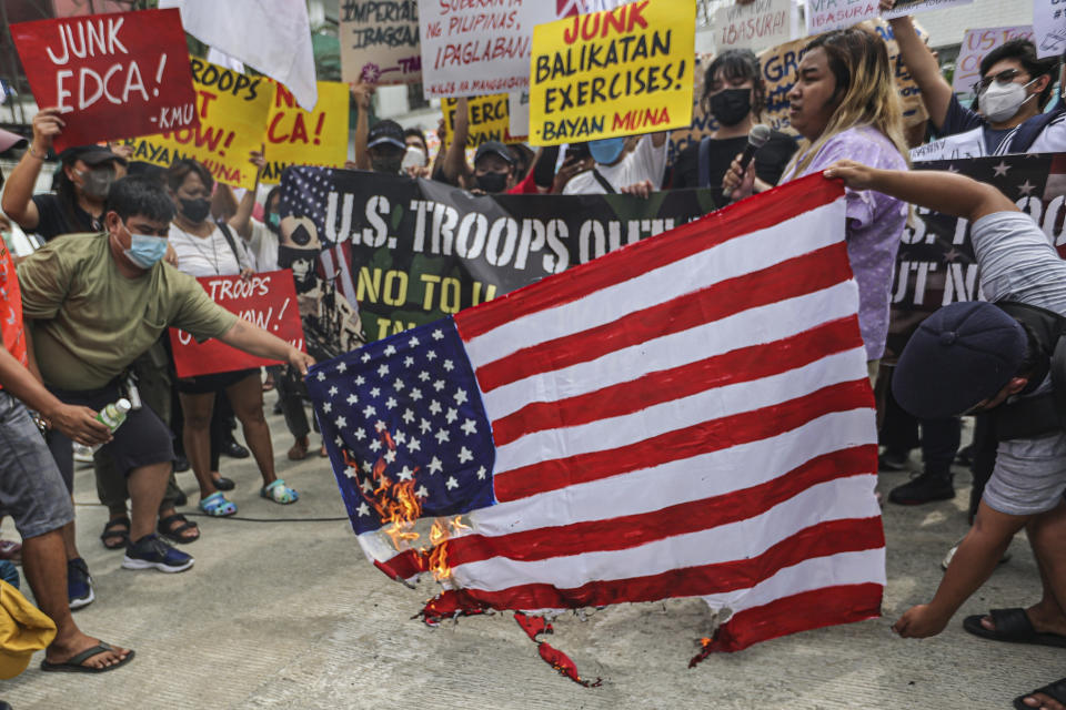 Demonstrators burn mock U.S. flag during rally in front of Camp Aguinaldo military headquarters in Quezon City, Philippines on Tuesday, April 11, 2023 as they protest against opening ceremonies for the joint military exercise flag called "Balikatan," Tagalog for shoulder-to-shoulder. The United States and the Philippines on Tuesday launch their largest combat exercises in decades that will involve live-fire drills, including a boat-sinking rocket assault in waters across the South China Sea and the Taiwan Strait that will likely inflame China. (AP Photo/Gerard Carreon)
