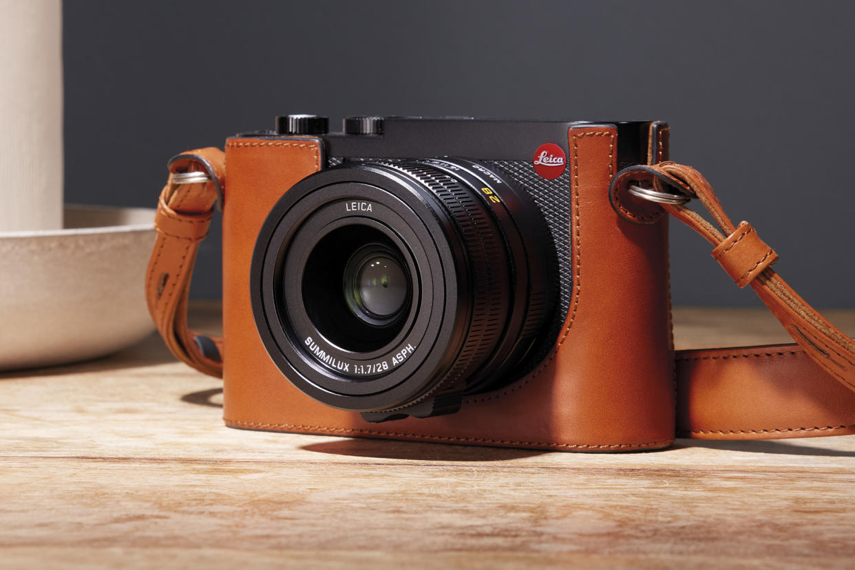  Leica Q3 in a brown leather case and on a wooden table 