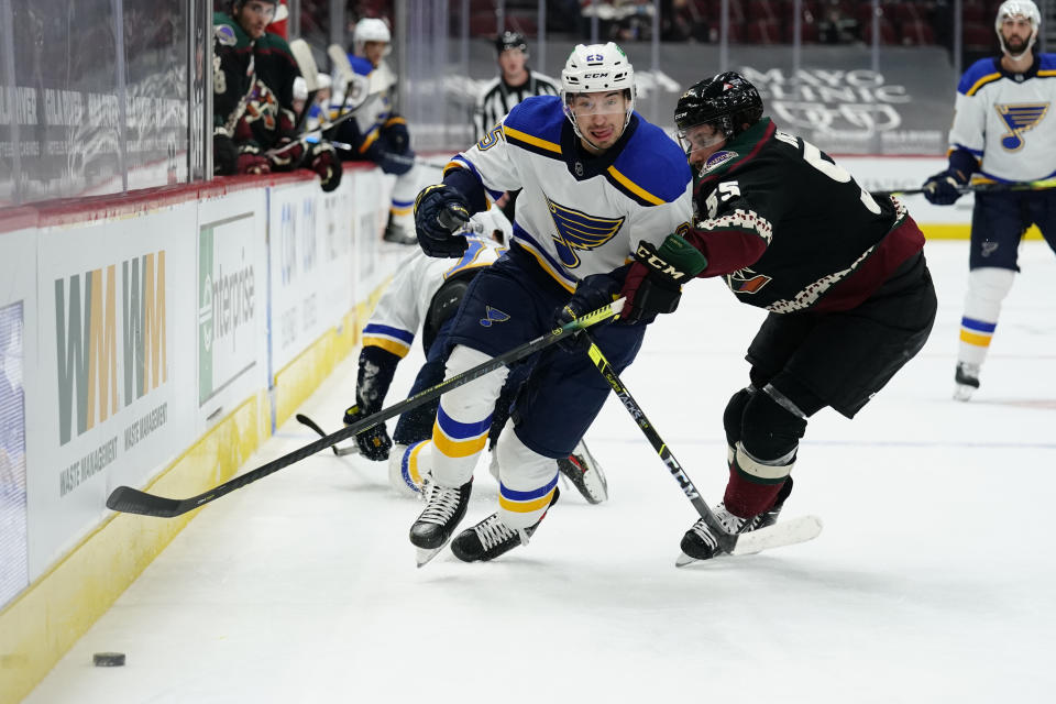 St. Louis Blues center Jordan Kyrou (25) and Arizona Coyotes defenseman Jason Demers battle for the puck in the first period during an NHL hockey game, Monday, Feb. 15, 2021, in Glendale, Ariz. (AP Photo/Rick Scuteri)