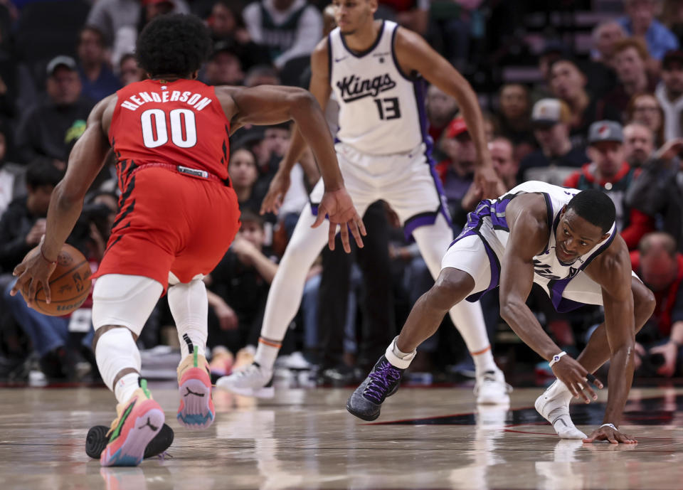 Sacramento Kings guard De'Aaron Fox, right, loses his shoe while guarding Portland Trail Blazers guard Scoot Henderson during the first half of an NBA basketball game Tuesday, Dec. 26, 2023, in Portland, Ore. (AP Photo/Howard Lao)