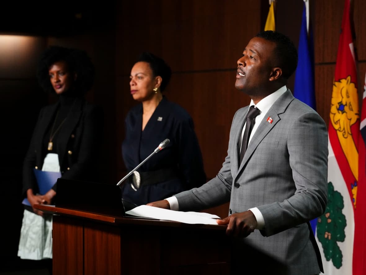 Nicolas Marcus Thompson (right), executive director of the Black Class Action Secretariat, speaks as Ketty Nivyabandi (left), secretary general of Amnesty International Canada, and Norma Domey (centre), national vice-president of the Professional Institute of Public Service of Canada (PIPSC), listen in during a press conference on Parliament Hill in Ottawa on Sept. 28. (Sean Kilpatrick/The Canadian Press - image credit)