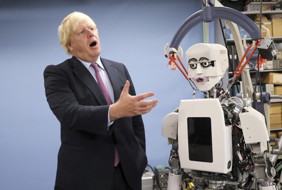 FILE - In this Thursday, July 20, 2017 file photo Britain's Foreign Secretary Boris Johnson gestures as he looks at a humanoid robot at Research Institute for Science and Engineering at Waseda University's campus in Tokyo. (AP Photo/Eugene Hoshiko, Pool, File)