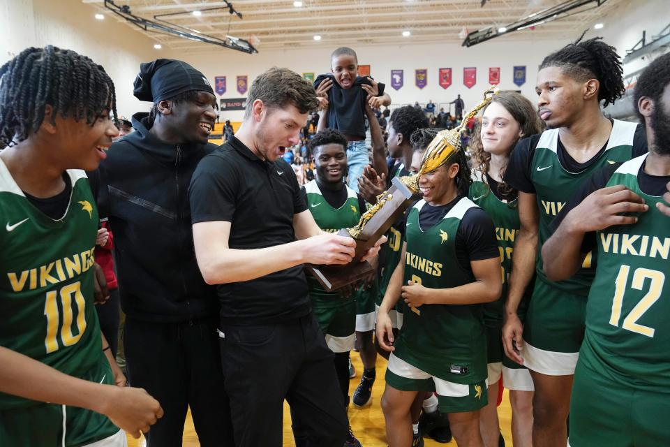 Northland assistant coach Leo Cleary-Foeller reacts to receiving the City League championship trophy after the Vikings beat South 63-46 on Saturday at East.