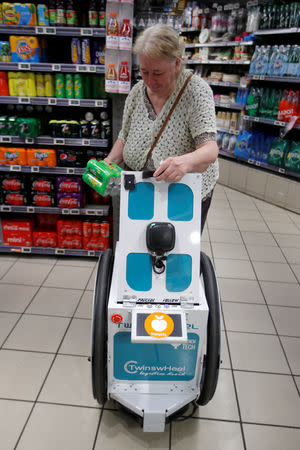 A woman does her shopping at a store using an autonomous robot, shaped and inspired by Star Wars R2D2, in a test for the delivery of groceries by Franprix supermarket chain in the 13th district of Paris, France, April 17, 2019. REUTERS/Charles Platiau