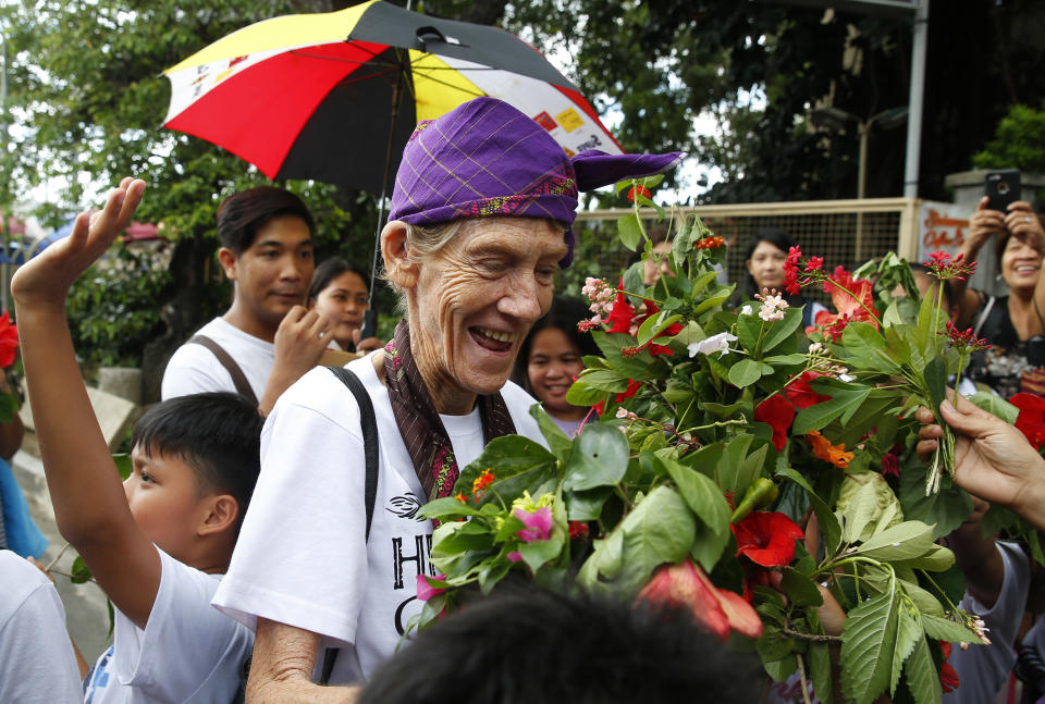 Australian Roman Catholic nun Sister Patricia Fox receives flowers from children of informal settlers as she arrives for a visit to the Redemptorist Church prior to her departure for Australia Saturday, Nov. 3, 2018 in suburban Paranaque city, south of Manila, Philippines. Sister Fox decided to leave after 27 years in the country after the Immigration Bureau denied her application for the extension of her visa. The Philippine immigration bureau has ordered the deportation of Fox who has angered the president by joining anti-government rallies. (AP Photo/Bullit Marquez)