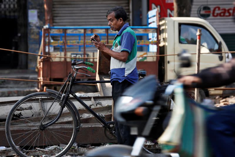 FILE PHOTO: A man checks his mobile phone as he stands on a busy road in Kolkata