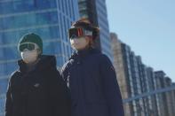 People wearing snow goggles and face masks are seen on a street, as the country is hit by an outbreak of the novel coronavirus, in Beijing's central business district