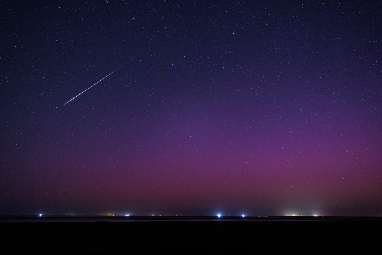 A shooting star from the Perseid meteor shower streaks through the night sky amid the vivid colors of aurora borealis over the North Sea near Pilsum, Germany, on Aug. 12, 2024. / Credit: Matthias Balk/picture alliance via Getty Images