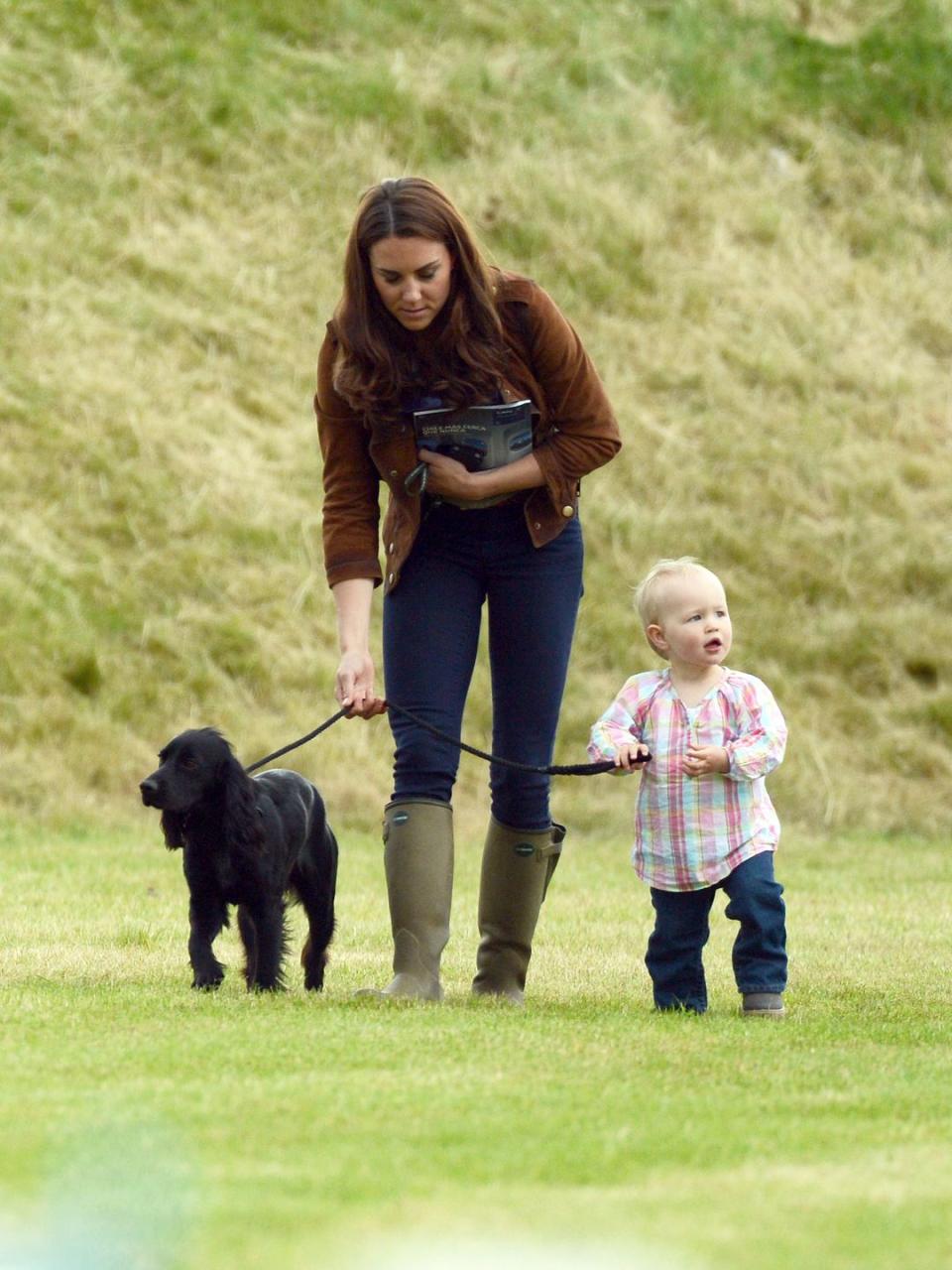 <p>The Duchess of Cambridge walks her dog, Lupo, with a 2-year-old Savannah Phillips. When Savannah was born in 2010, she was the first great-grandchild for Queen Elizabeth. </p>