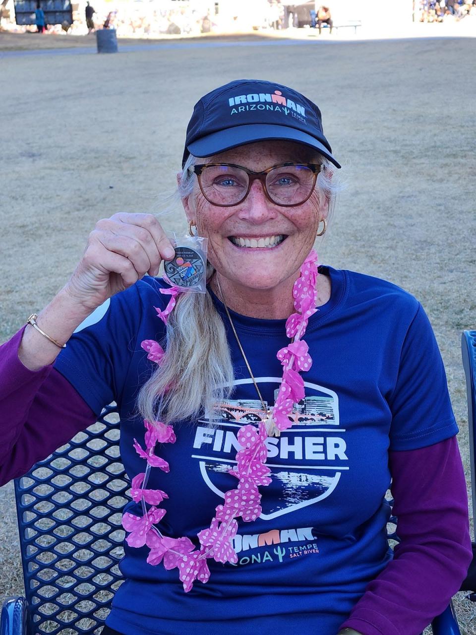 Leslie Maurice holds her finisher medal after completing an Ironman triathlon event in Kona, Hawaii, the tenth such race she's completed.