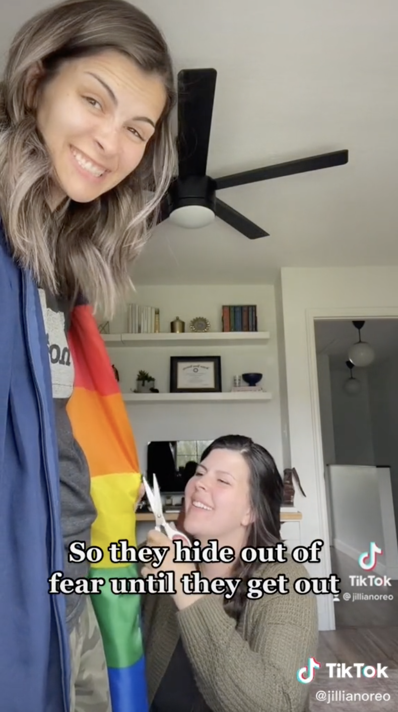 Jillian wearing the robe as her sister puts the finishing touches on the stitching of the Pride flag