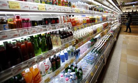 A woman looks at drinks at a supermarket at Ginza shopping district in Tokyo October 31, 2013. The Bank of Japan maintained its massive stimulus programme at a policy review on Thursday, and later in the day is expected to slightly revise up its economic growth forecast to around 1.5 percent for the next fiscal year. REUTERS/Yuya Shino