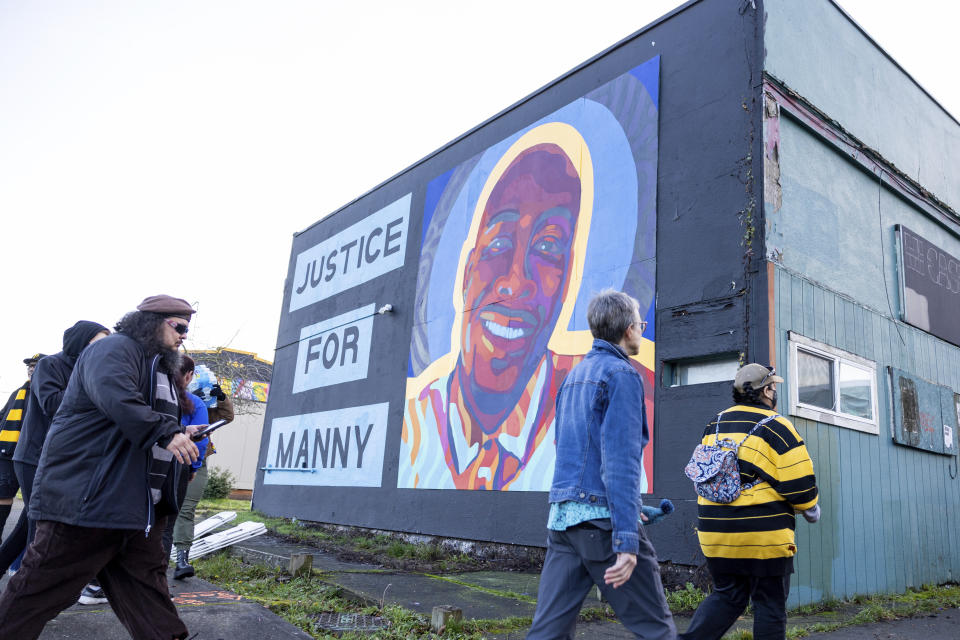 FILE - Protesters walk by a mural of Manny Ellis after the verdict is read during the trial of three Tacoma police officers in the death of Ellis, Dec. 21, 2023, at Pierce County Superior Court in Tacoma, Wash. Three Washington state police officers who were cleared of all criminal charges last month in the 2020 death of Ellis will each receive $500,000 to leave the Tacoma Police Department, according to documents released, Tuesday, Jan. 16, 2024. (AP Photo/Maddy Grassy)