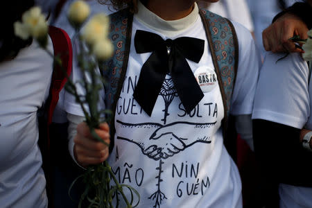 A nurse with a black bow and white carnation is seen during a protest march in Lisbon, Portugal, March 8, 2019. REUTERS/Pedro Nunes